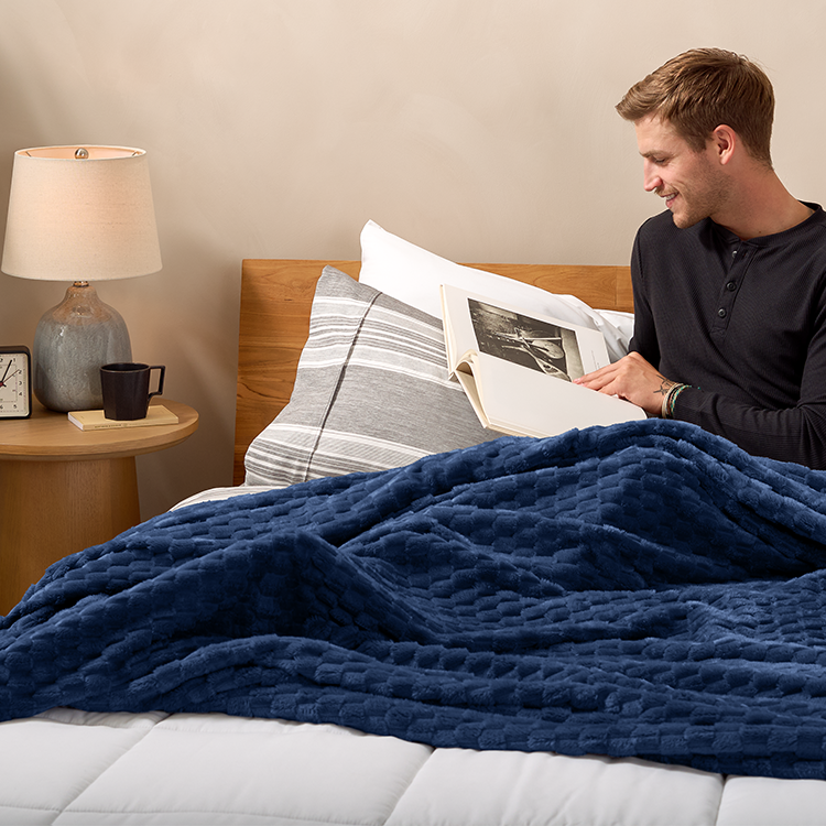 Man reading in bed with navy blue Microplush Ribbed Blanket