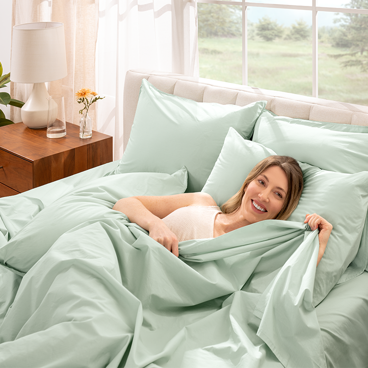 Woman relaxing in bed with sage green Organic Cotton Percale Bedding Bundle