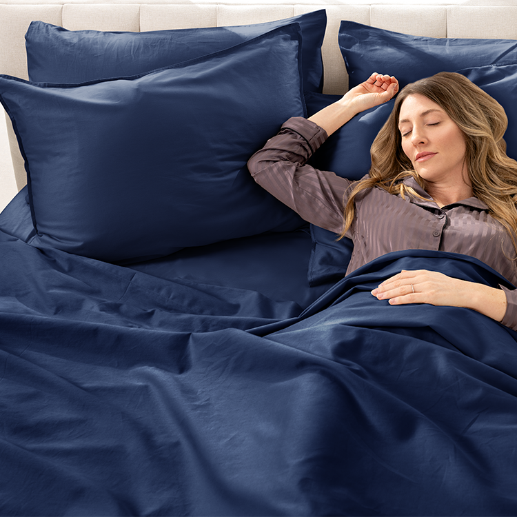 Woman relaxing in bed with navy blue Organic Cotton Sateen Sheet Set