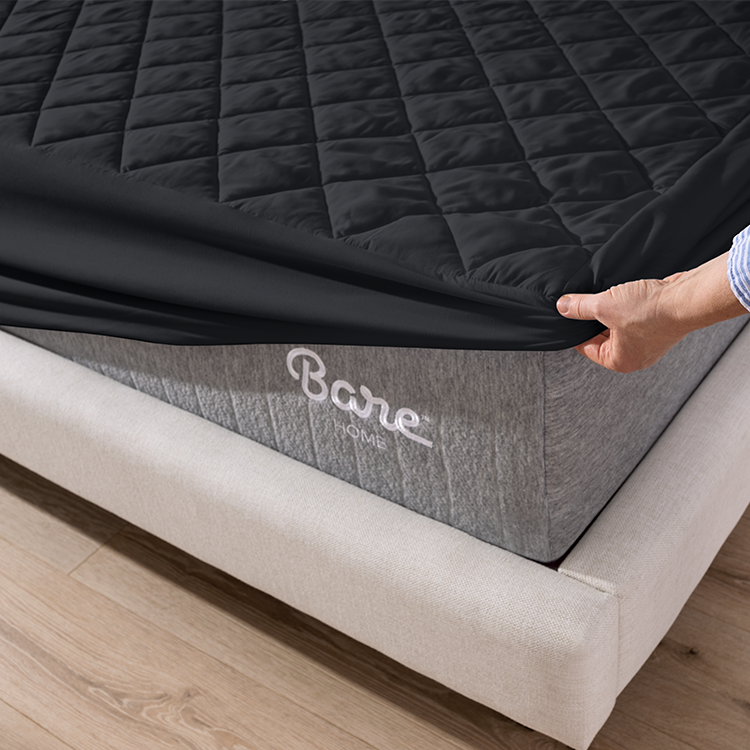 Closeup of dark gray Quilted Mattress Pad fitted onto a mattress corner