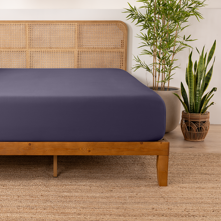 Bed with a navy bamboo fitted sheet on a wood bed frame