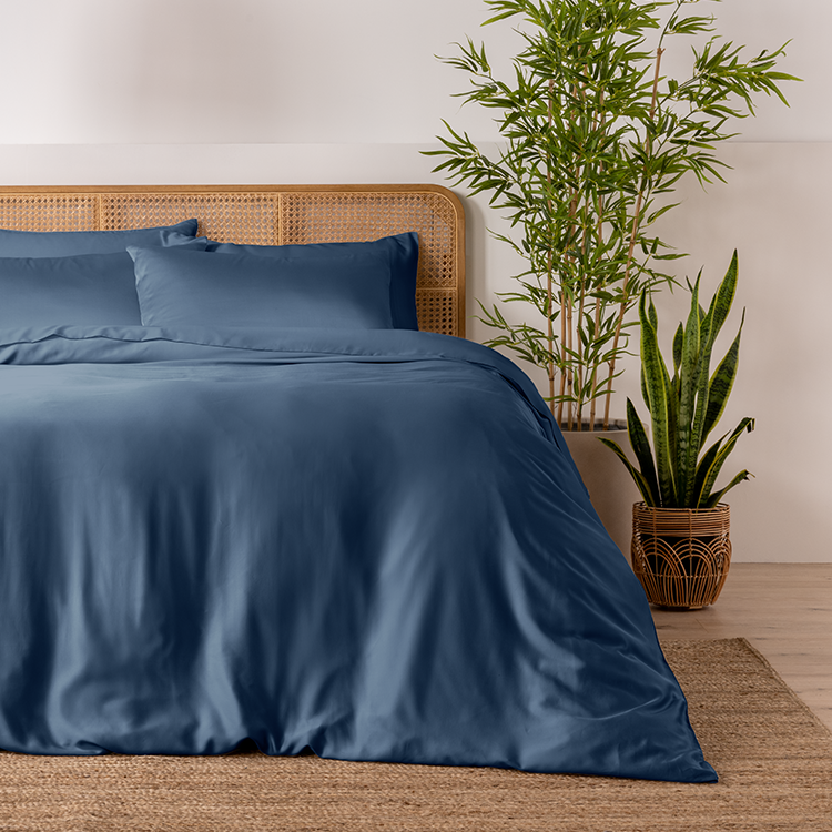 Bed with navy blue bamboo sheets next to a plant