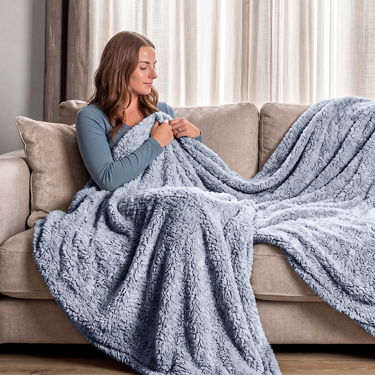 Woman sitting on a couch wrapped in a blue tipped sherpa blanket