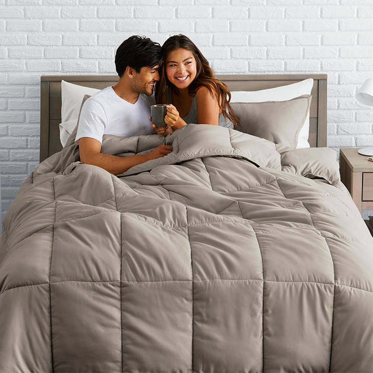 Couple sitting under a taupe Ultra Soft Box Stitch Comforter Set