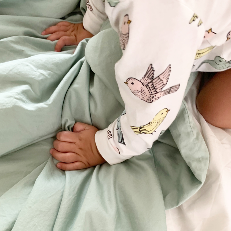 Crib with a sage green fitted sheet