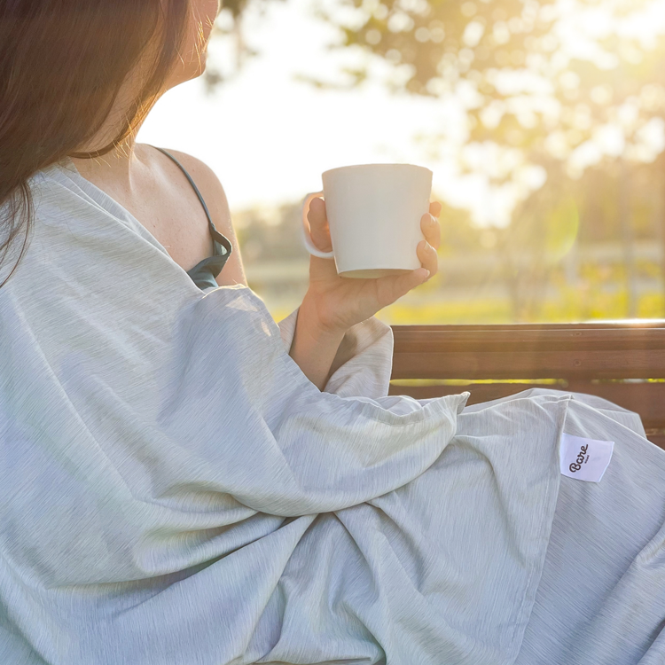 Woman holding a mug in bed with light blue Ultra Soft Heather Sheet Set