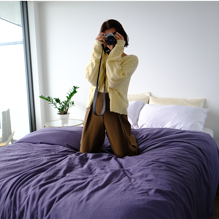 Woman sitting on a bed with dark purple Ultra Soft Washed Duvet Cover Set