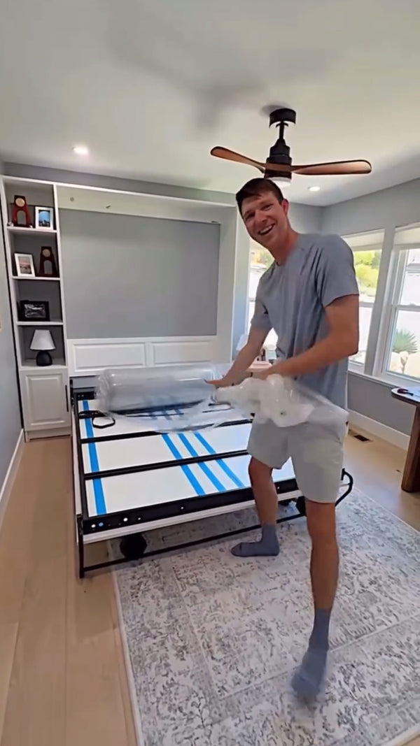 Man unraveling a new mattress on a bed frame
