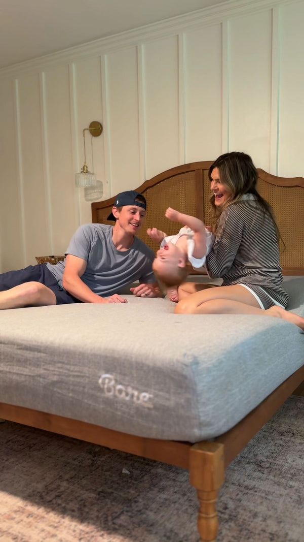 couple and baby playing on a new mattress