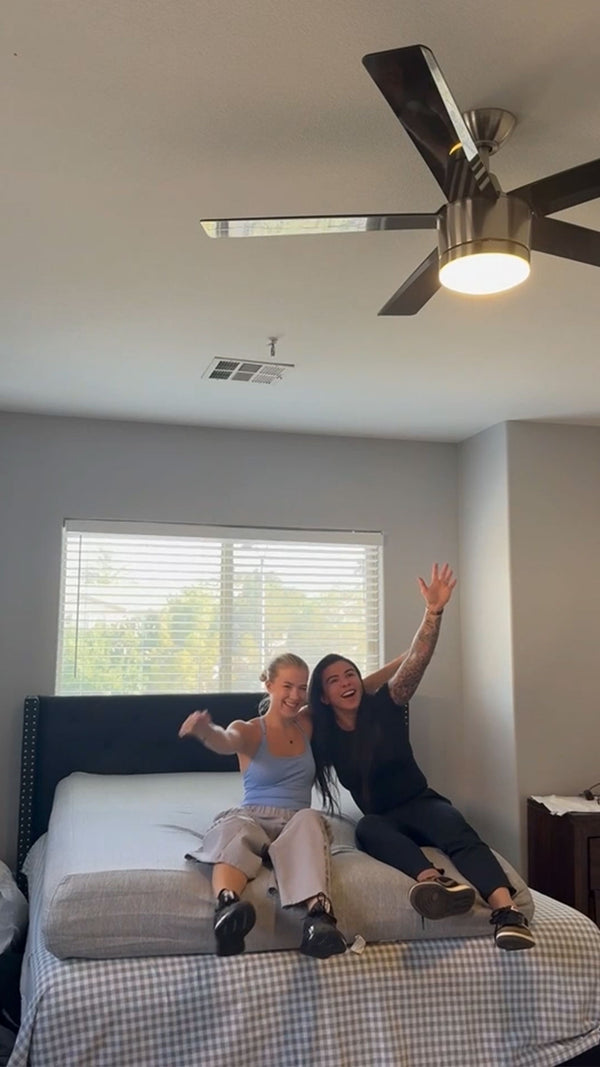 Two ladies sitting on a new mattress just unrolled
