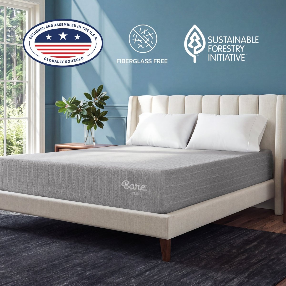 A gray Bare Mattress on a cream upholstered bed frame in a styled bedroom setting with a blue wall, wooden headboard, and decorative pillows.