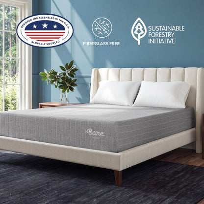 A gray Bare Mattress on a cream upholstered bed frame in a styled bedroom setting with a blue wall, wooden headboard, and decorative pillows.