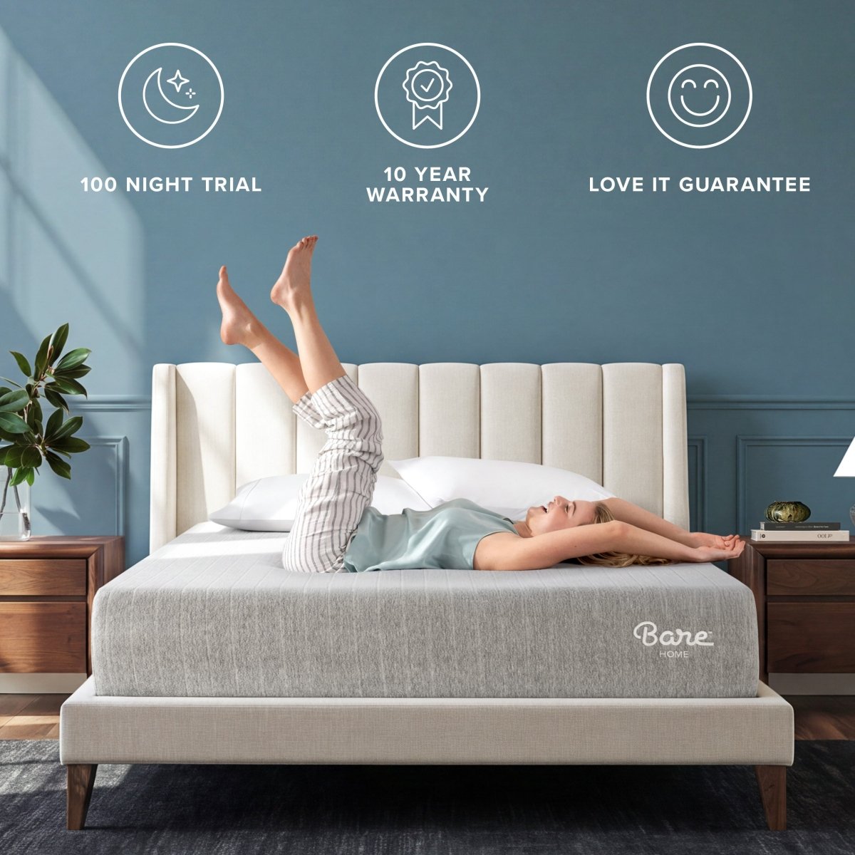 A woman lies stretched out on a light gray Bare Mattress on a bed with a cream tufted headboard in a styled bedroom. 