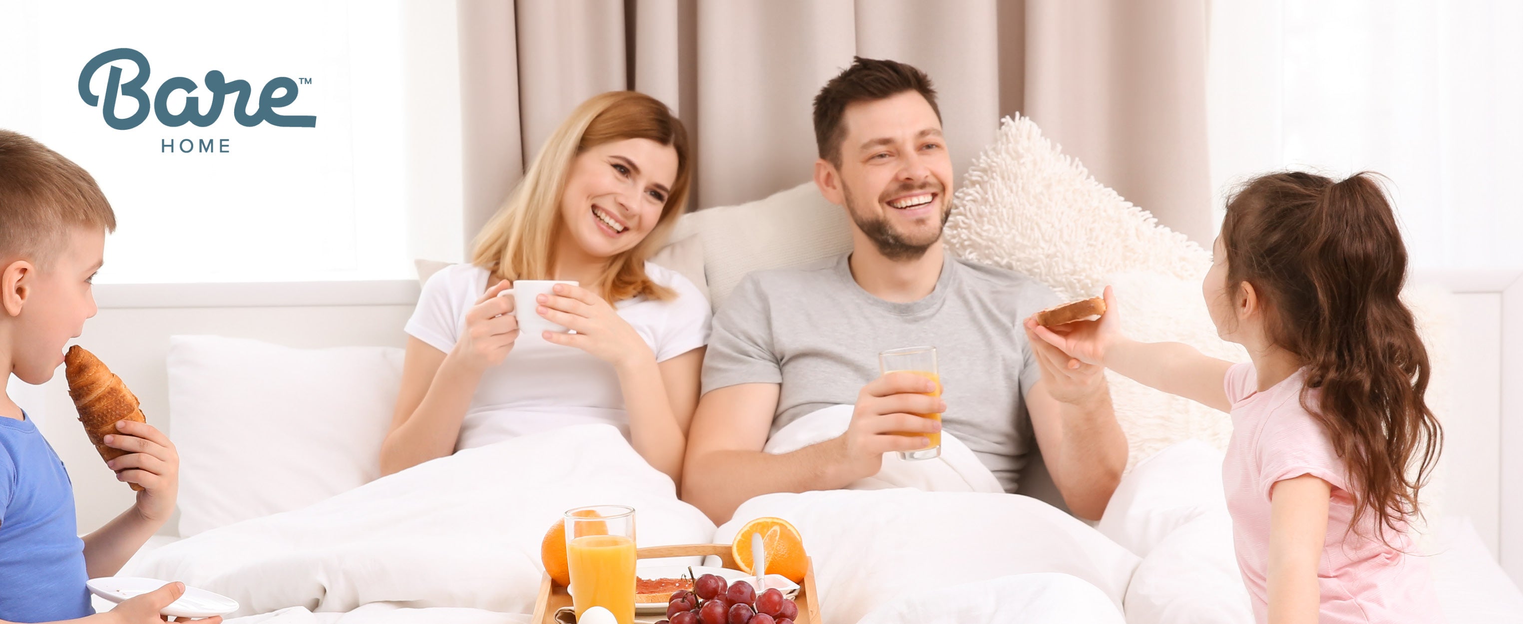 Family in bed eating breakfast with kids