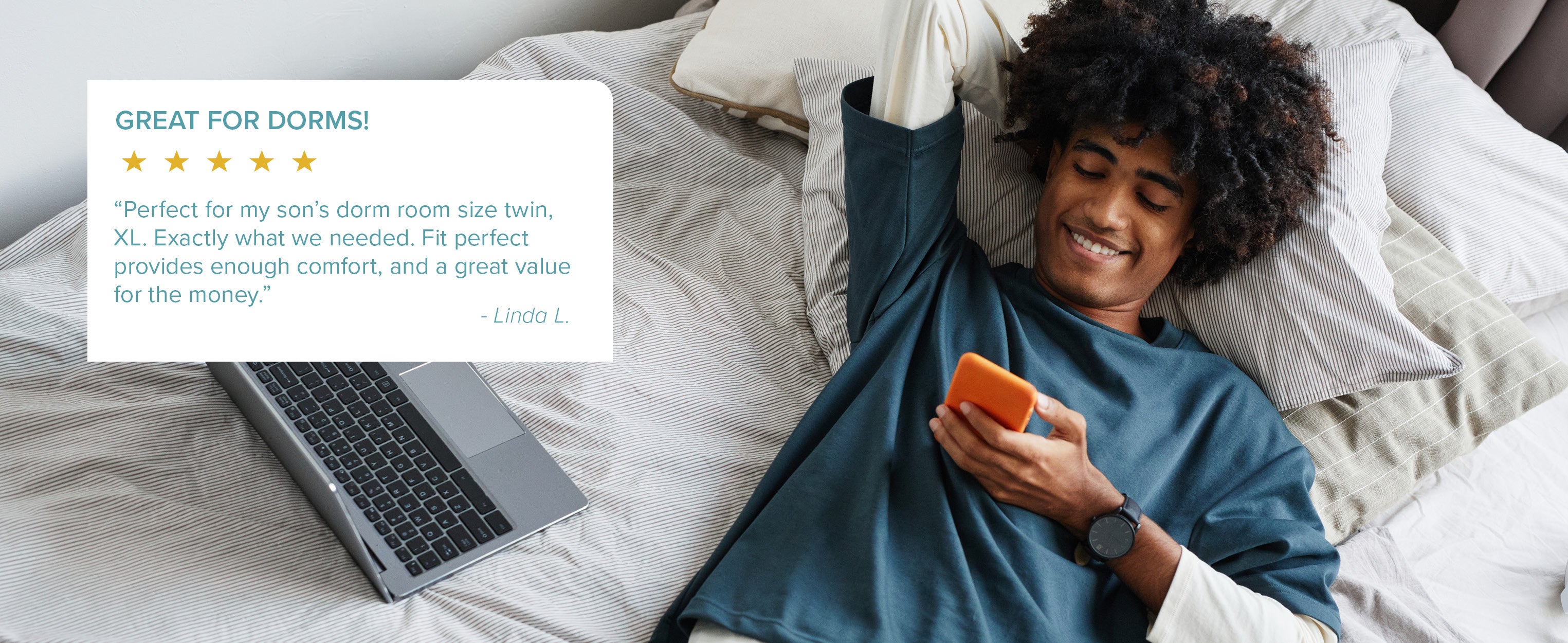 student laying on bed looking at mattress pad reviews on his phone