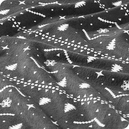 A close-up of dark gray fabric with a white winter pattern featuring snowflakes and Christmas trees