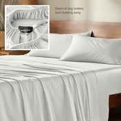 Bamboo sheets with a sewn-in tag on a wooden bed frame.