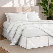 A modern bedroom with a bed skirt, comforter and sheets on the bed