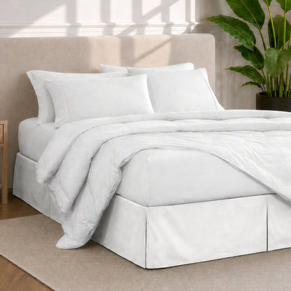 A modern bedroom with a bed skirt, comforter and sheets on the bed