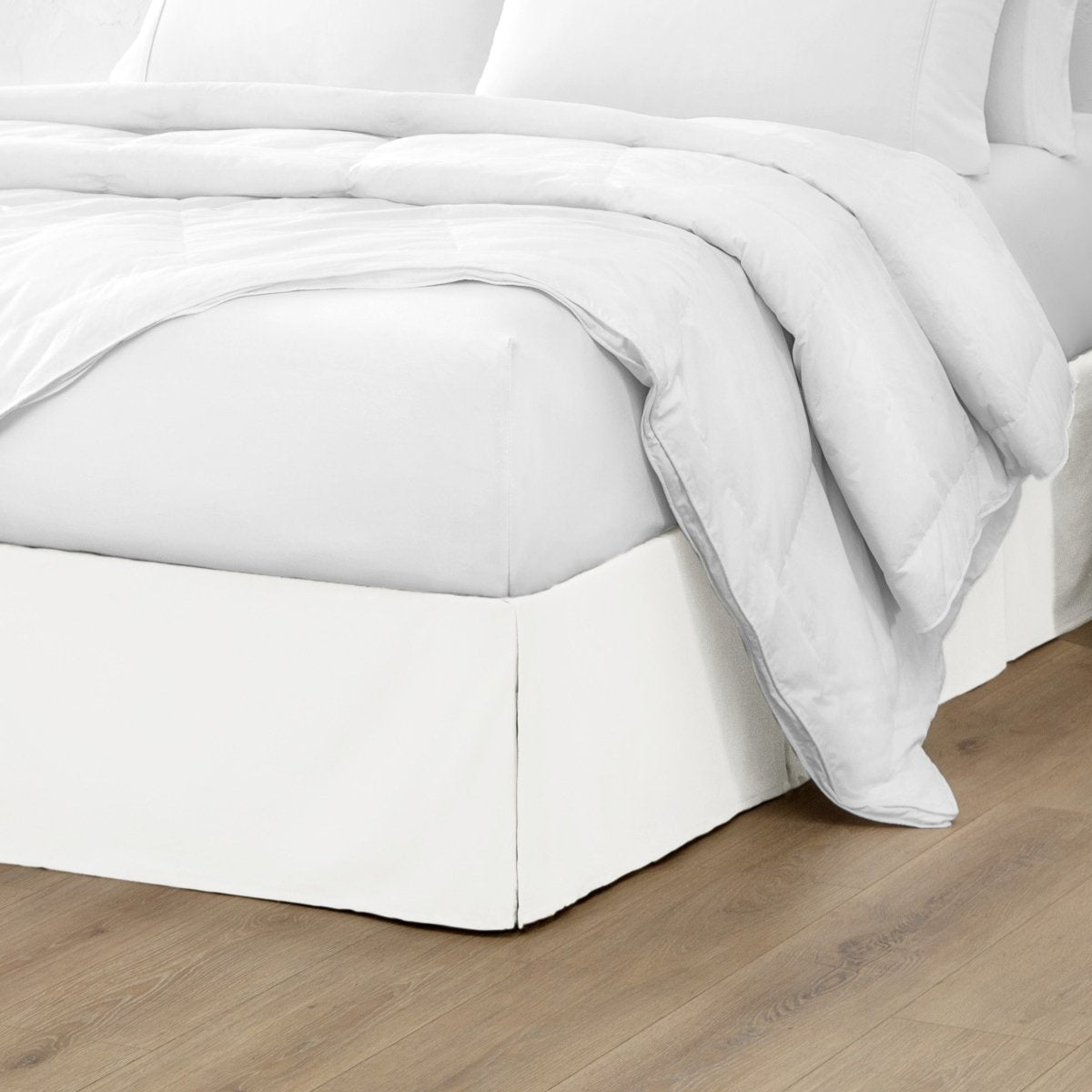 Microfiber bed skirt on a bed with white bedding and wooden floor.