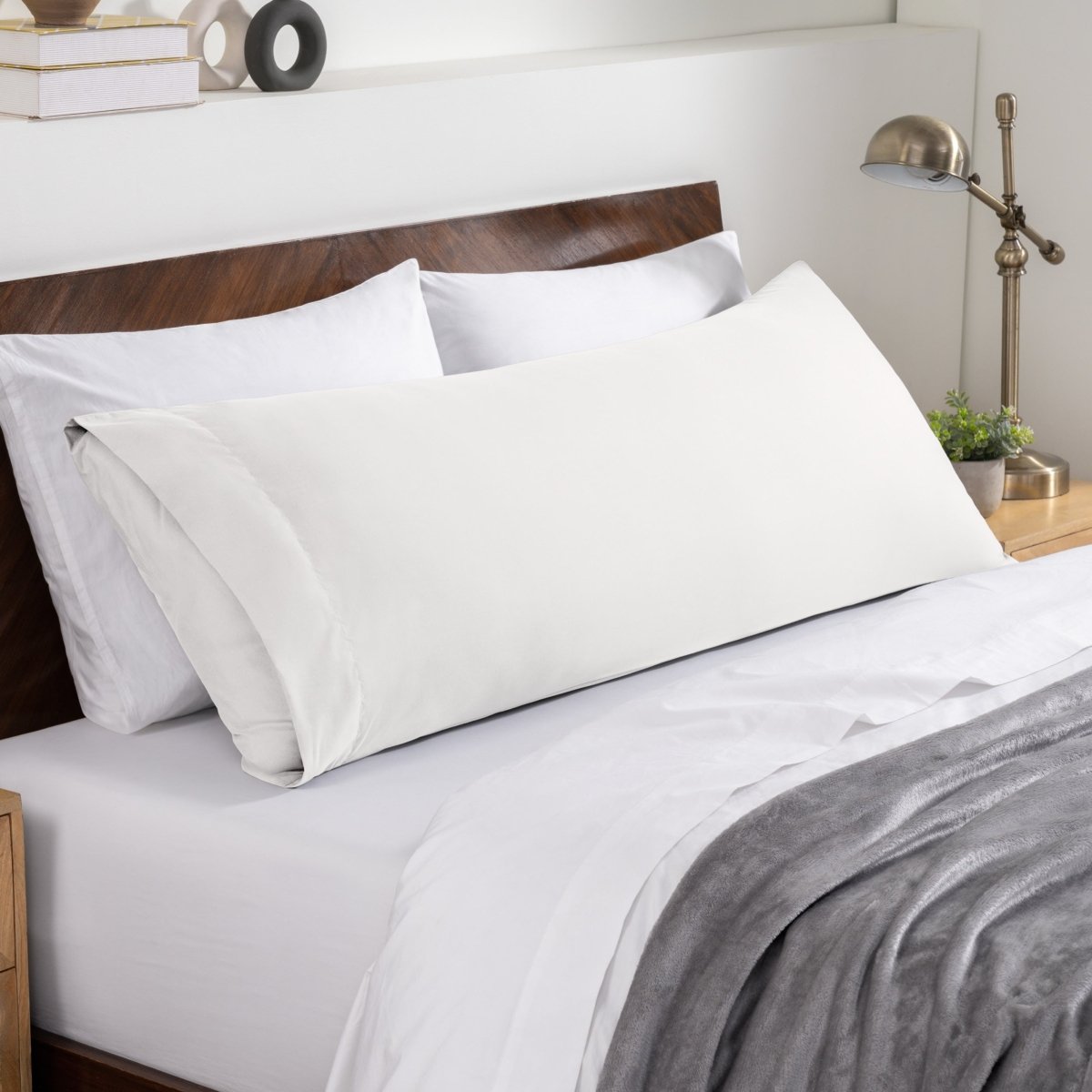 Bed sheets and pillows on a neatly made bed with a wooden headboard.
