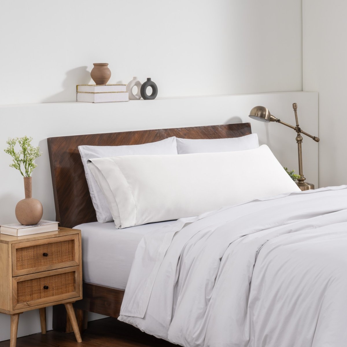 Bedroom with a wooden headboard and white bedding, featuring a nightstand and decorative items.