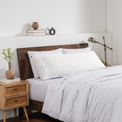 Bedroom with a wooden headboard and white bedding, featuring a nightstand and decorative items.