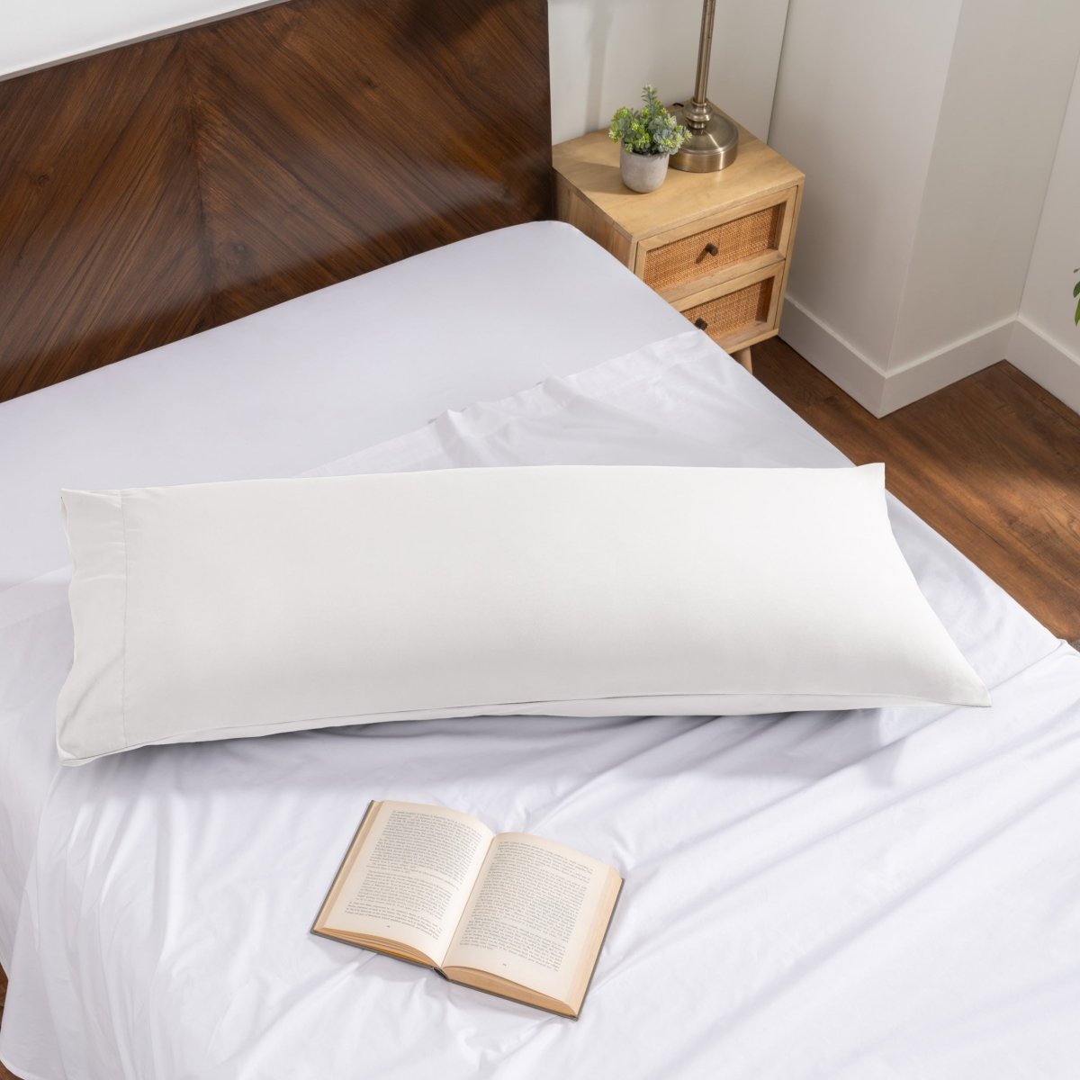 Pillowcase on a body pillow with a wooden headboard and plant in the background