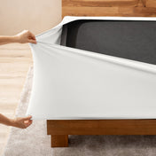 A person stretching a box spring cover