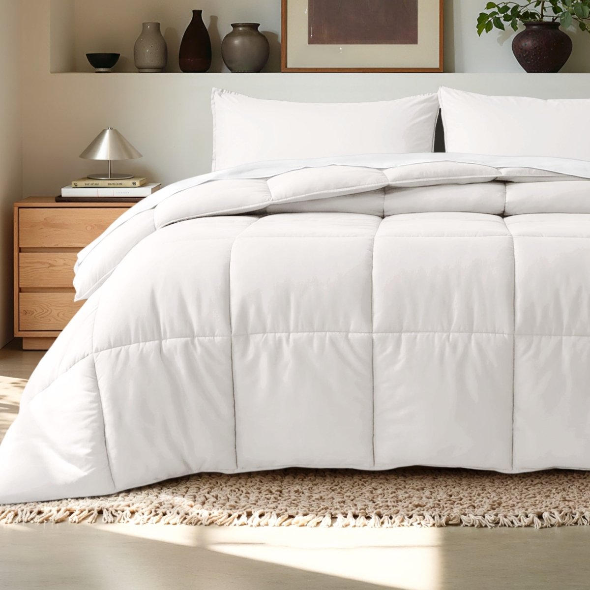 Comforter on a bed in a bedroom setting with a wooden nightstand and decorative items.