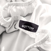 A close-up of a fitted sheet with a label printed with the word 'BOTTOM' in white.