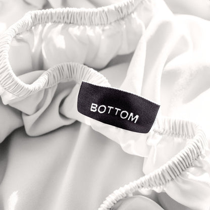 A close-up of a fitted sheet with a label printed with the word 'BOTTOM' in white.