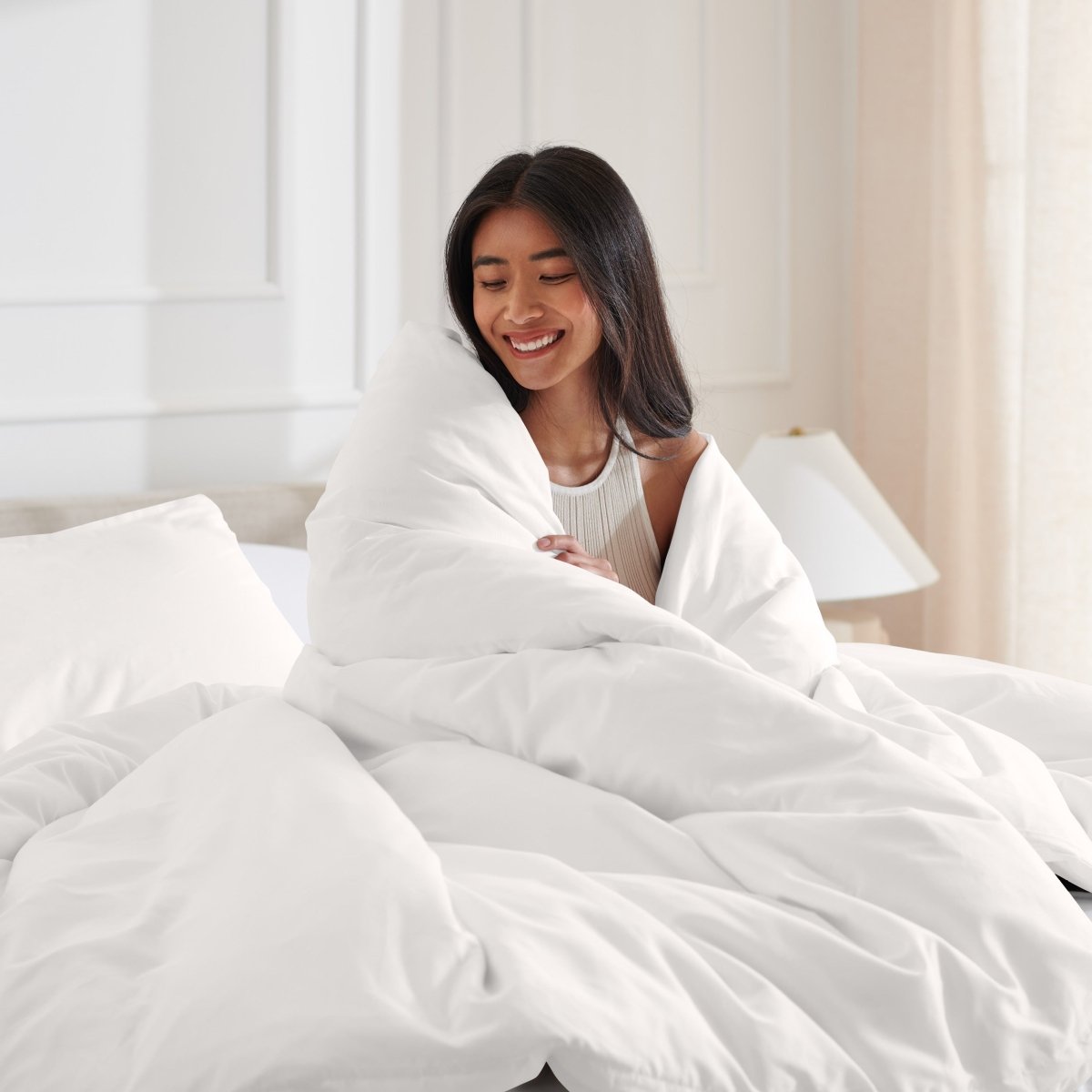 Woman smiling under duvet cover set in a bedroom setting