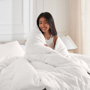 Woman smiling under duvet cover set in a bedroom setting
