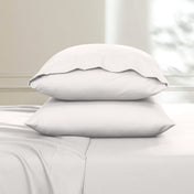Two pillows stacked on a bed with a neutral background