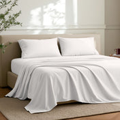 Microfiber sheets on a bed in a well-lit room with a plant.