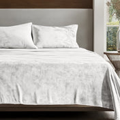 Microplush sheet set on a bed in a bedroom setting with a nightstand and lamp.
