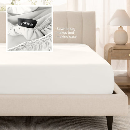 A fitted bed sheet shown on a bed. Text on the image says the sewn-in tag makes bed-making easy.