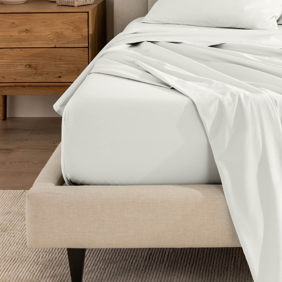 Top sheet and a matching fitted sheet on a bed with a beige bed frame