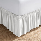 Bed with white fitted sheet and an adjustable bed skirt.