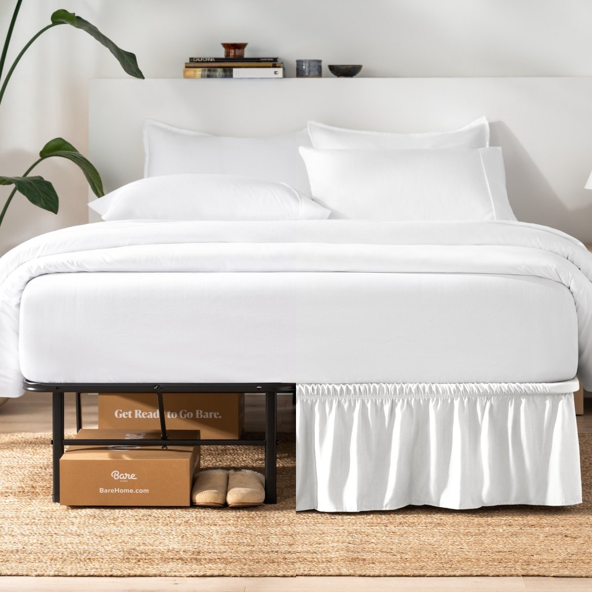 Bed with white bedding and a plant near the bed.