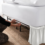 Adjustable bed skirt on a bed showing the elastic strap.