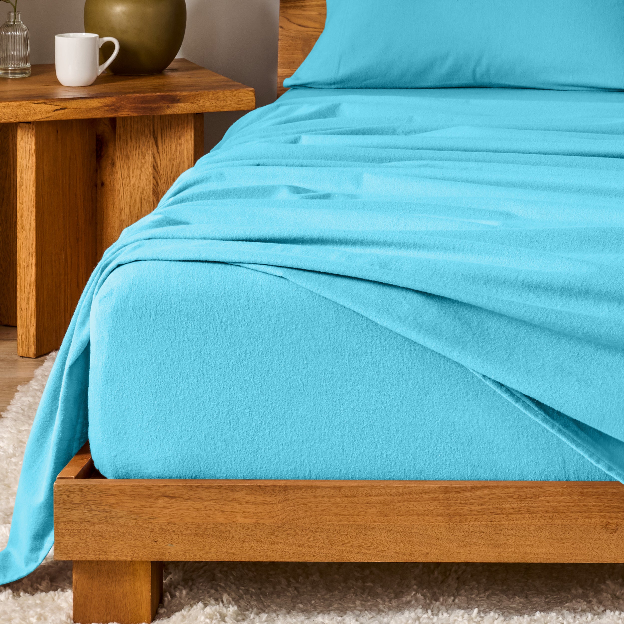 Bed with flannel bedding and wooden headboard and nightstand next to it.