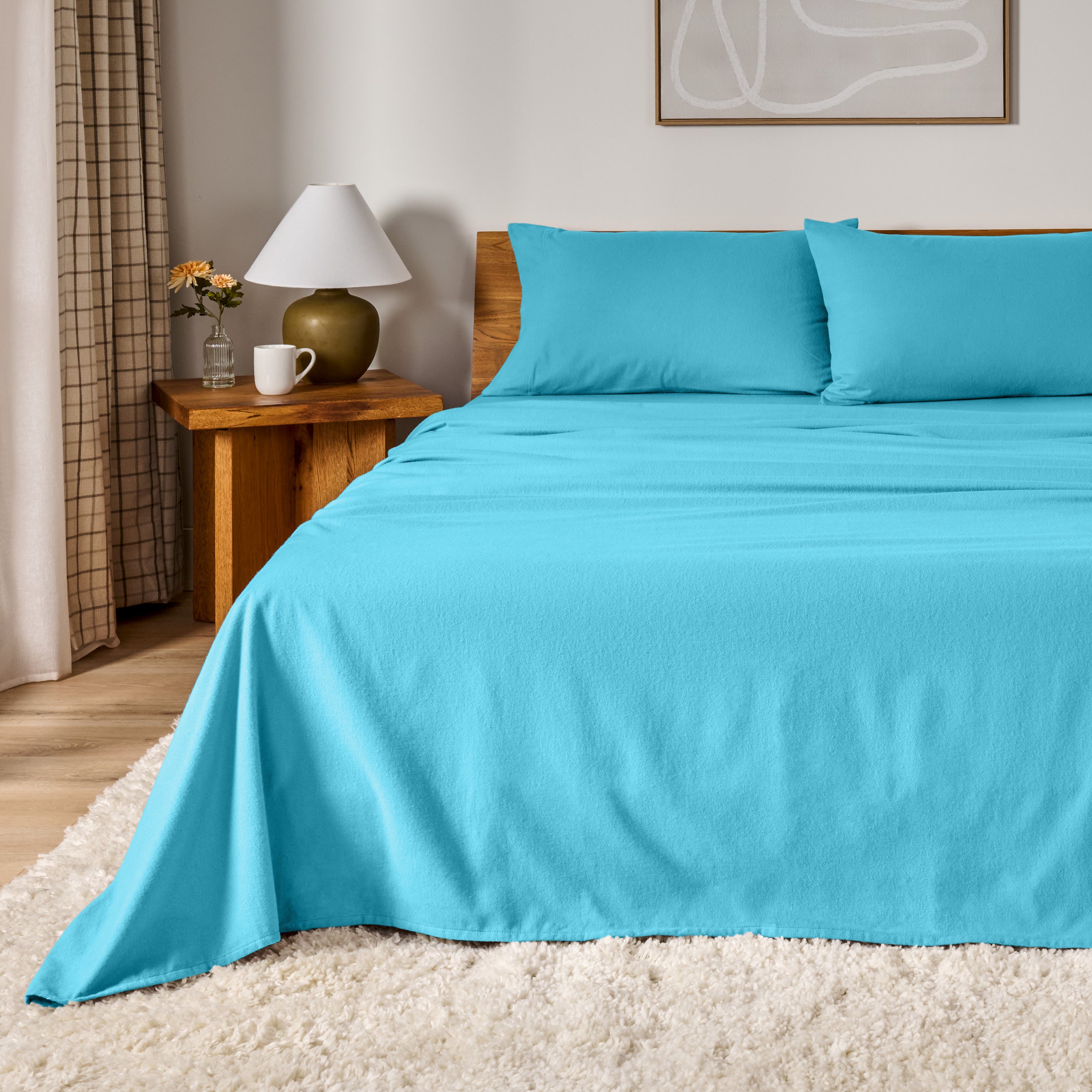 A bed dressed in flannel sheet set in a bedroom with a wooden headboard, bedside table and lamp