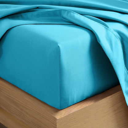A close-up of a fitted sheet covering the corner of a bed frame, with matching top sheet draped over it.