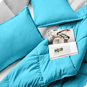 Close up of a comforter set on a bed. There are glasses and a magazine on top of the comforter.