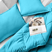 Close up of a comforter set on a bed. There are glasses and a magazine on top of the comforter.