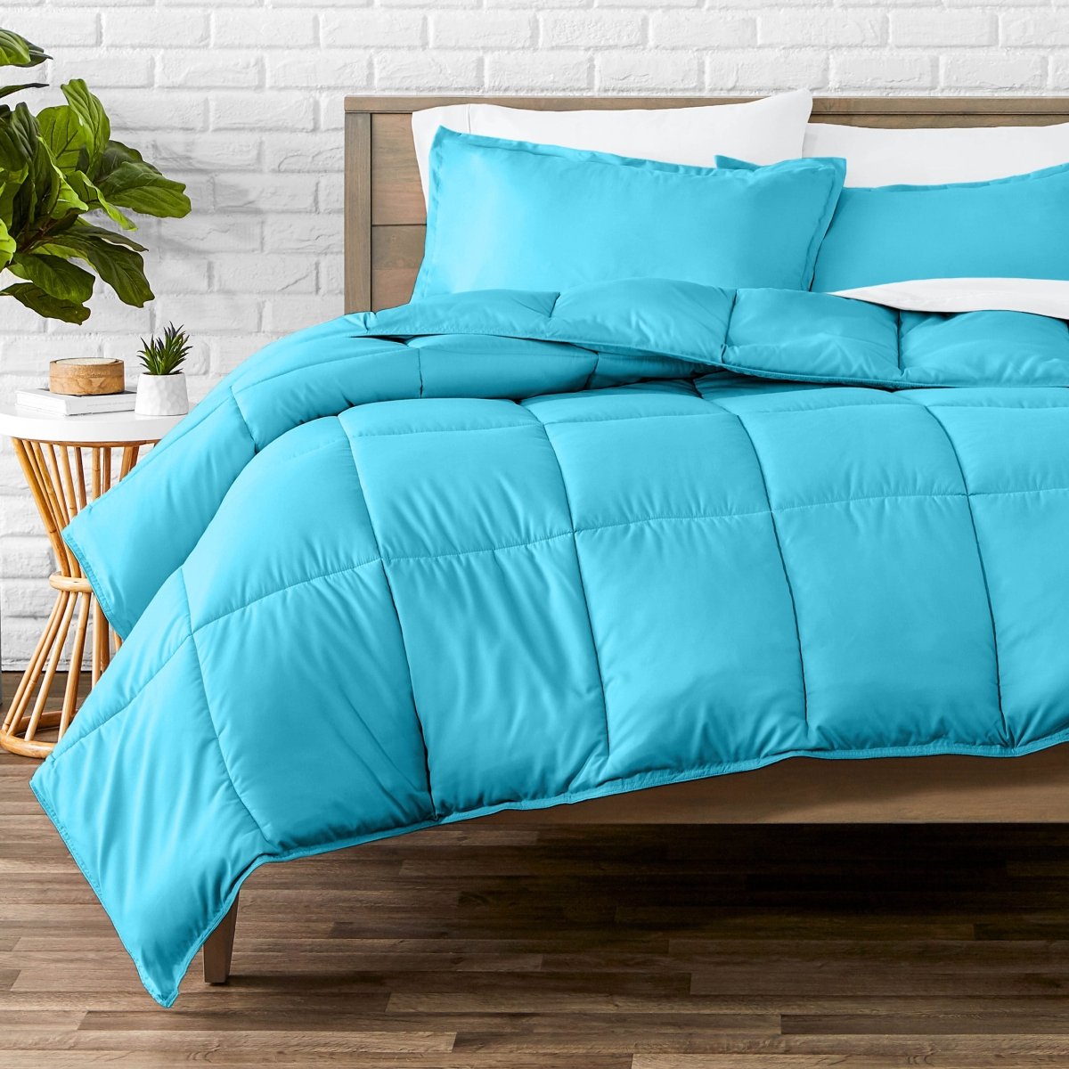 Comforter set on a bed with a white brick wall and plant in the background