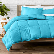 Comforter set on a bed with a white brick wall and plant in the background