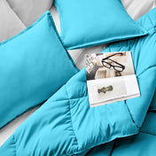 Comforter and pillows on a bed with a magazine and glasses.